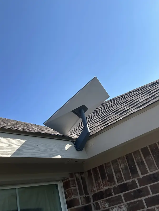 Starlink dish mounted at the roof edge of a brick home