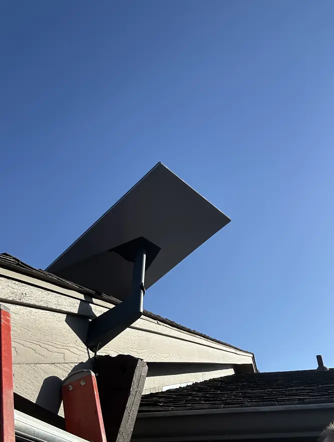 Starlink dish on a roof-edge bracket, with the installer's ladder at the gutter
