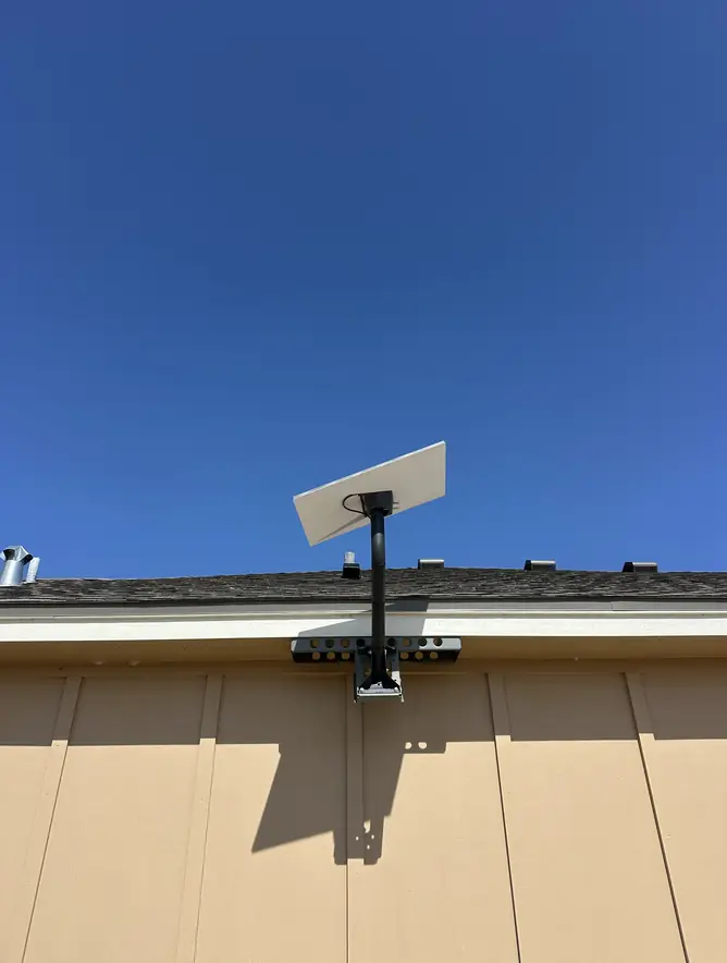 Starlink dish on a wall bracket that lifts it just above the roofline