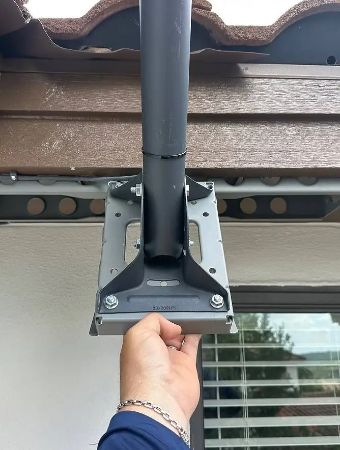 Starlink pole mount bracket being fitted beneath a tile roof